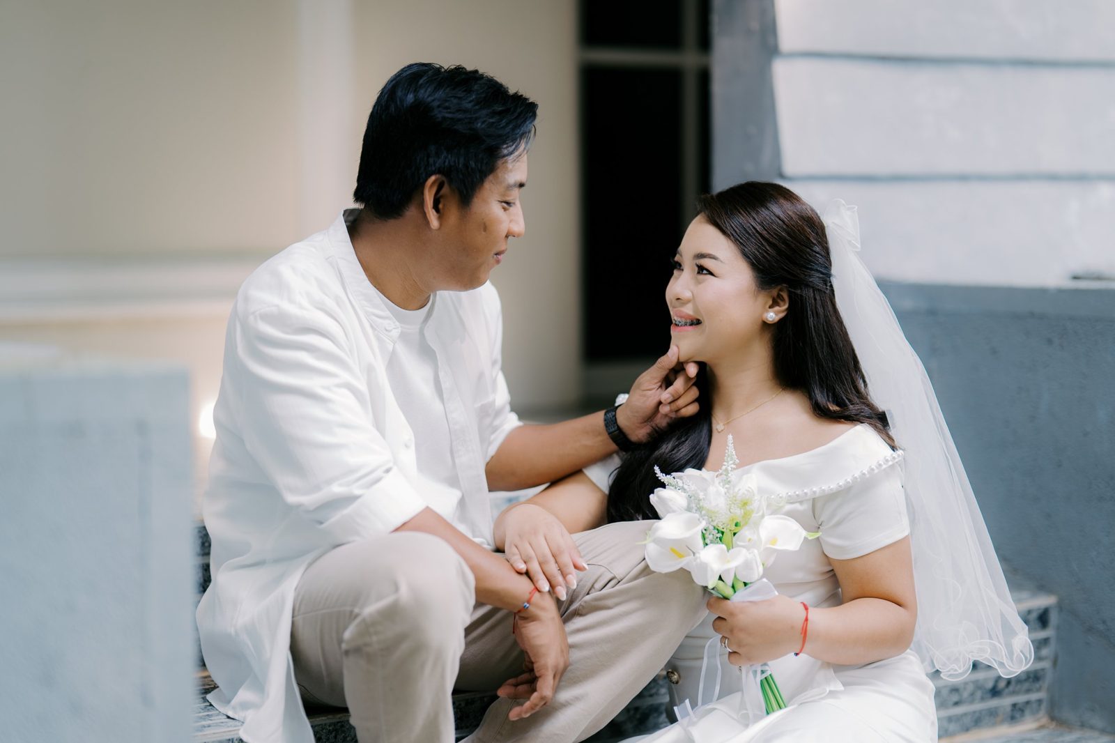 Arnaldo gently holding Regine's chin as she smiles up at him, bouquet of calla lilies in hand
